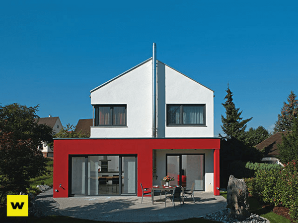Modernes Einfamilienhaus mit roter Fassade und Garten bei sonnigem Wetter.